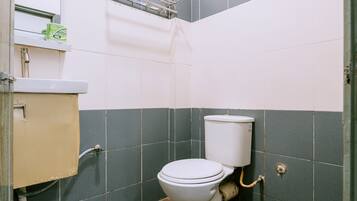A small bathroom with a toilet, a sink, and a window.