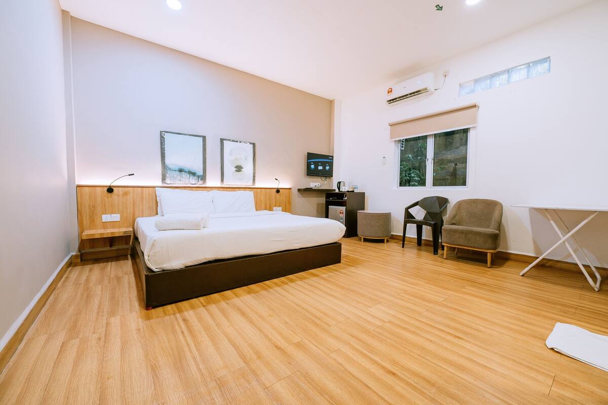 A modern bedroom with a large bed, a desk, a chair, and a small table.