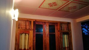 A room with wooden-framed windows, a light fixture on the wall, and a ceiling with a floral pattern.