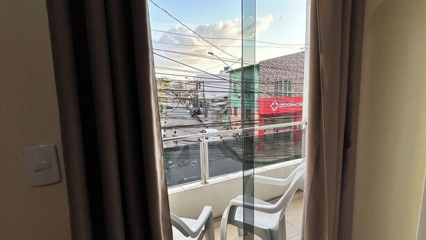 Ein Balkon mit Plastikstühlen und einer Glastür.