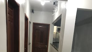 Ein schmaler Flur mit einer Holztür, einer schwarzen Matte und einer Metalltreppe.