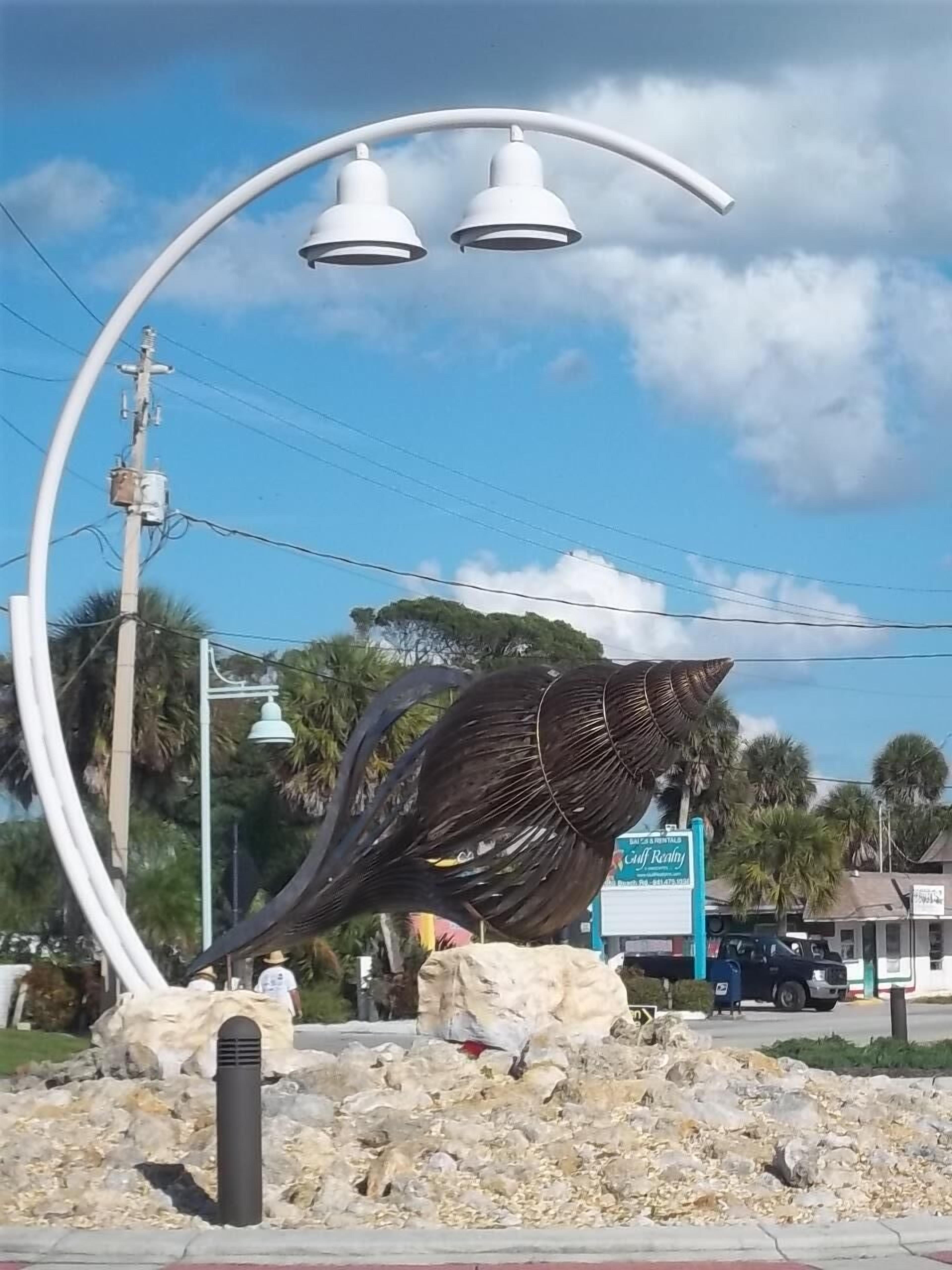 A street lamp with three white lights, a large bird sculpture, and a sign for Gulf Realty.