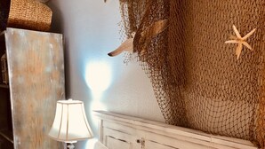 Una cama bien tendida con ropa de cama blanca y una almohada con el texto "Life's other beach".