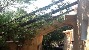 Une structure en pierre en forme d’arche, recouverte de plantes grimpantes, qui fait partie d’un bâtiment au style rustique.