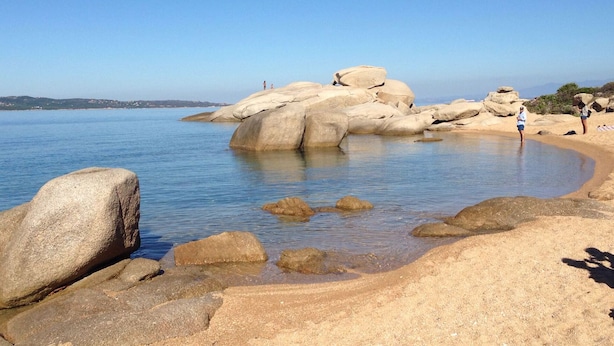 Une plage rocheuse avec une eau claire et de gros rochers.