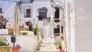 Una calle estrecha con edificios blancos, una escalera y plantas en macetas.