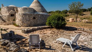 Un edificio de piedra con techo cónico, rodeado de terreno rocoso y vegetación escasa.