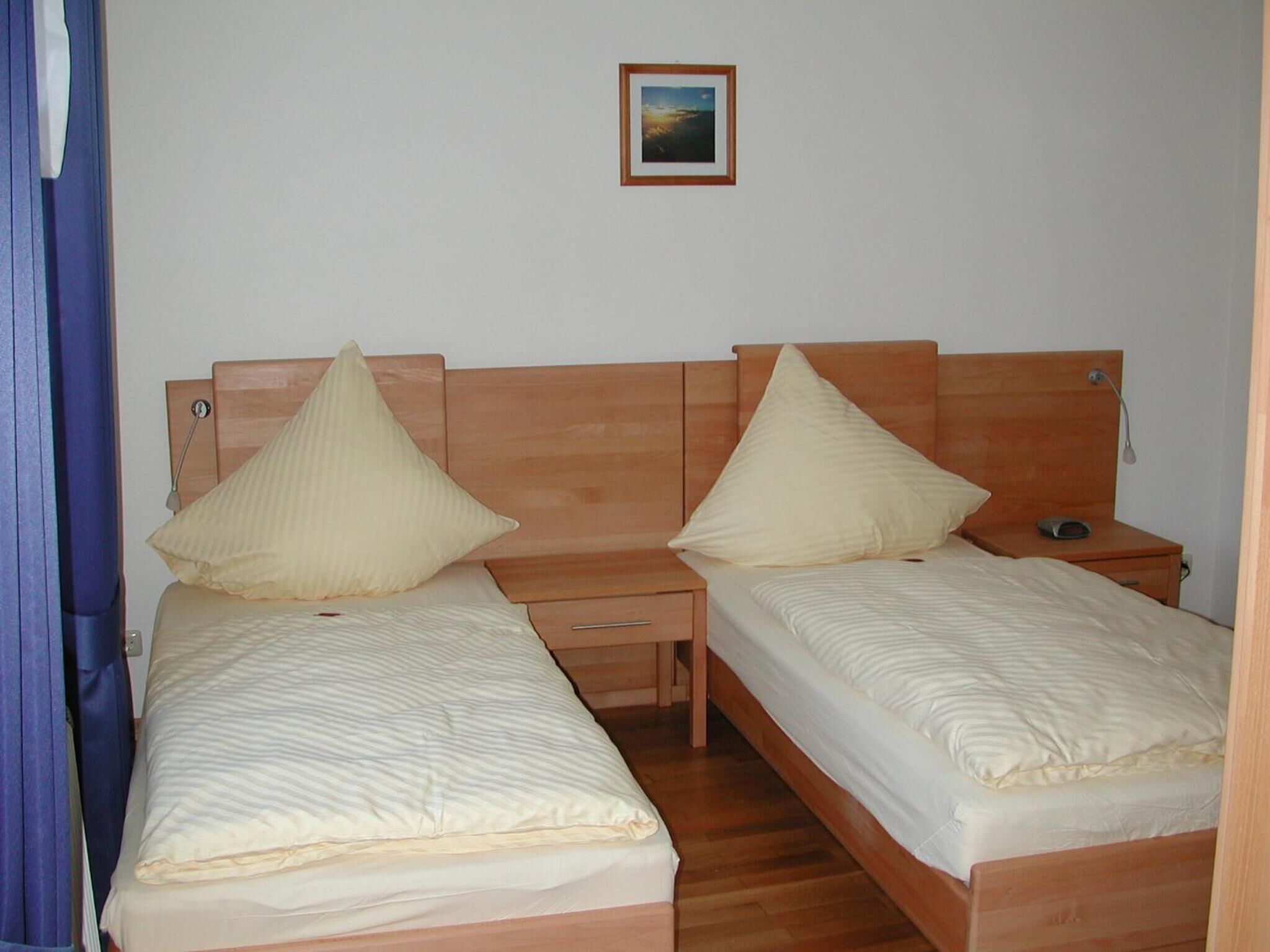 A twin room with two single beds, wooden headboards, bedside tables, and a small bedside lamp.