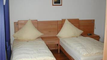 A twin room with two single beds, wooden headboards, bedside tables, and a small bedside lamp.