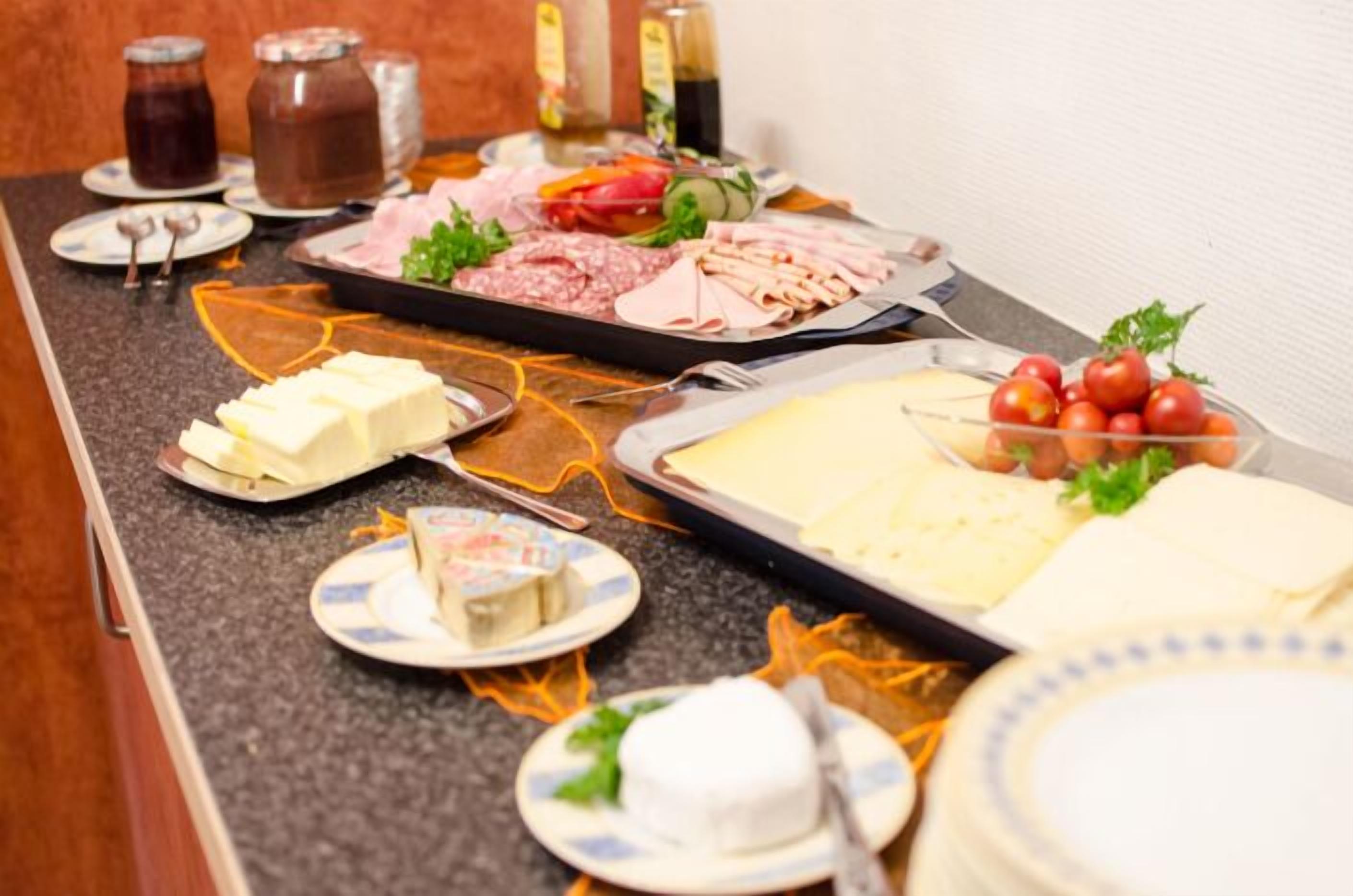 A buffet table with various food items including meats, cheeses, and vegetables.