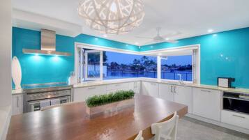 A modern kitchen with a wooden island, stainless steel appliances, and a view of a body of water at dusk.