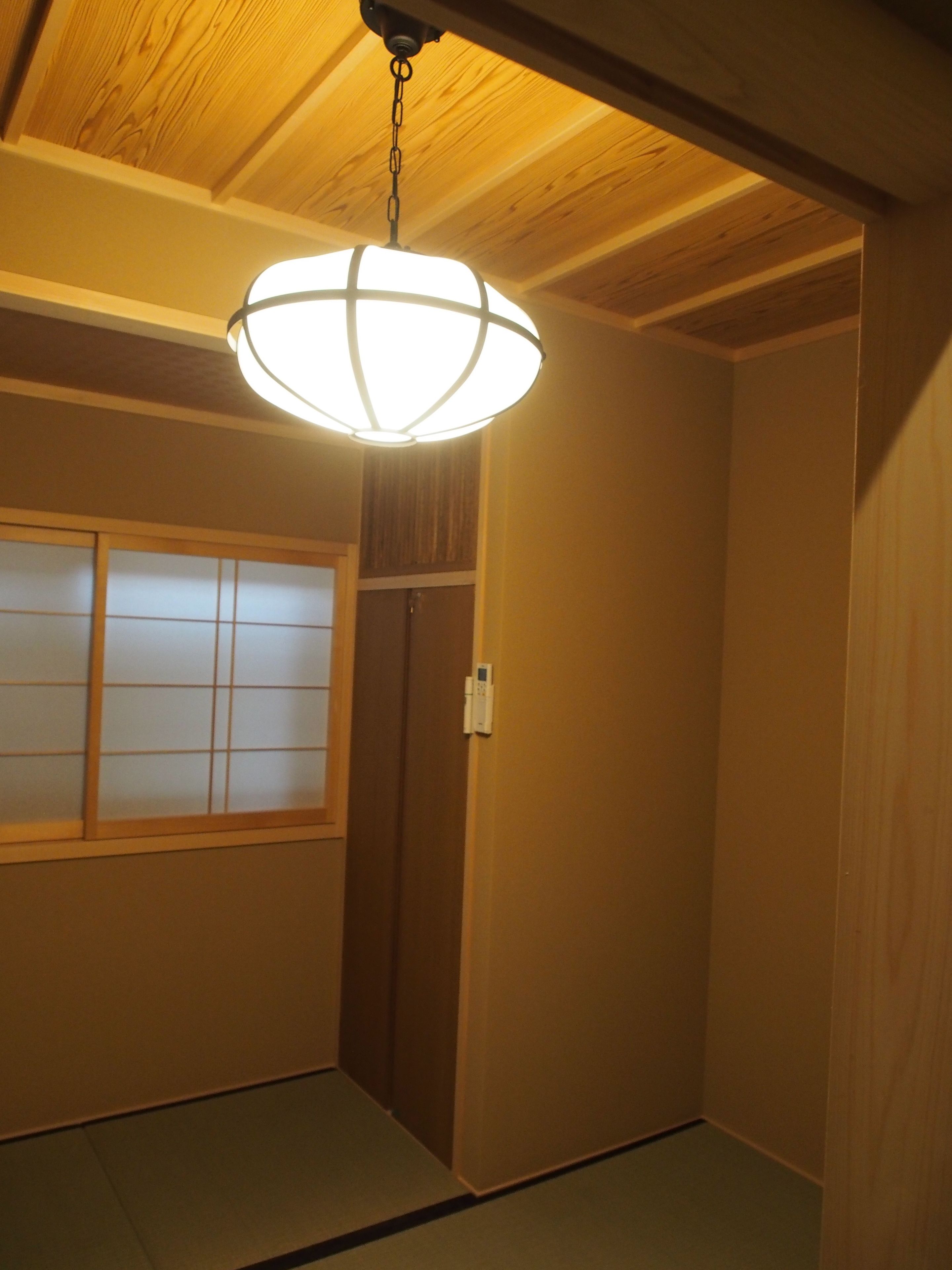 A room with a wooden ceiling, a sliding door, and a traditional Japanese shoji screen.