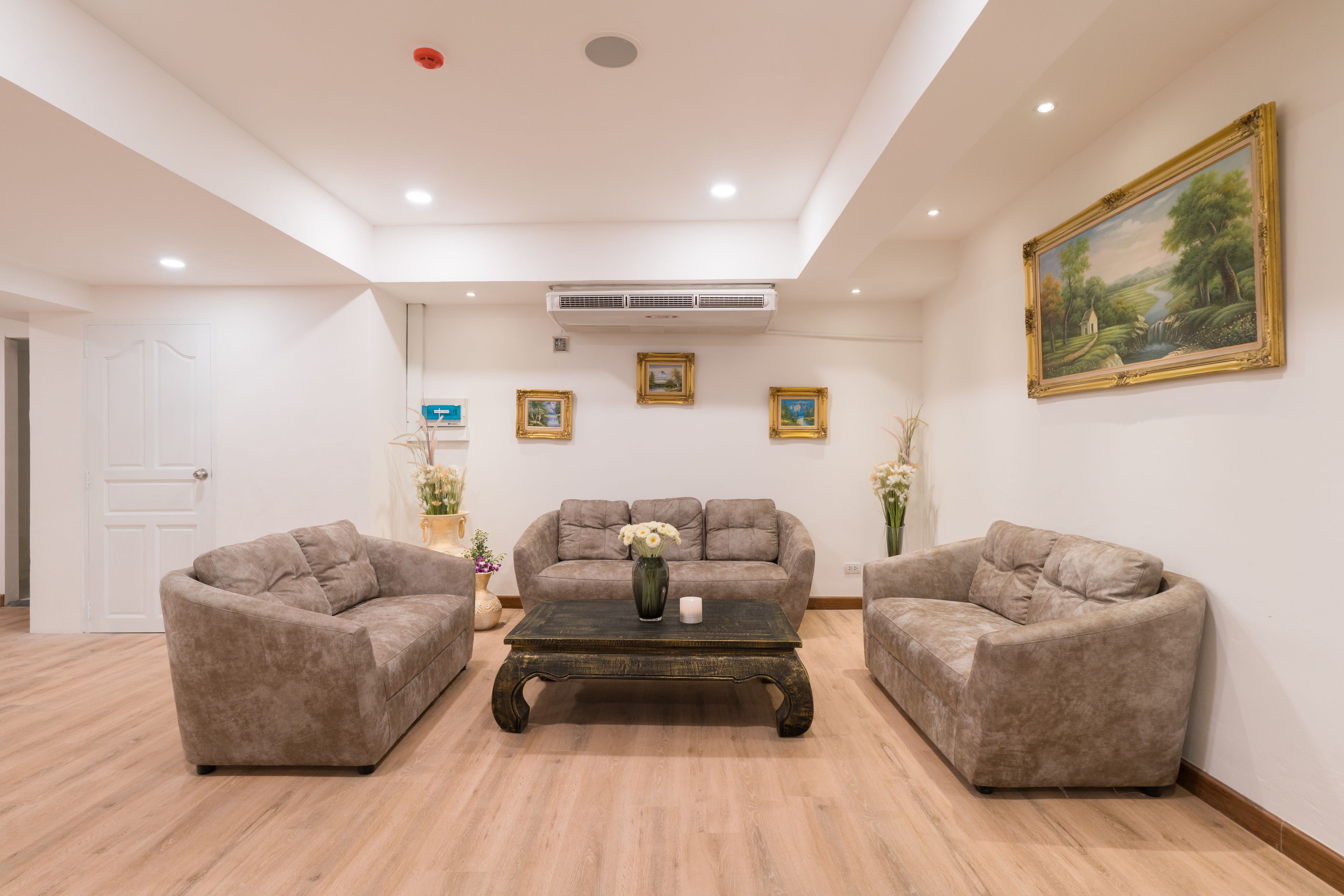 Una sala de estar con tres sofás, una mesa de centro y un cuadro en la pared.