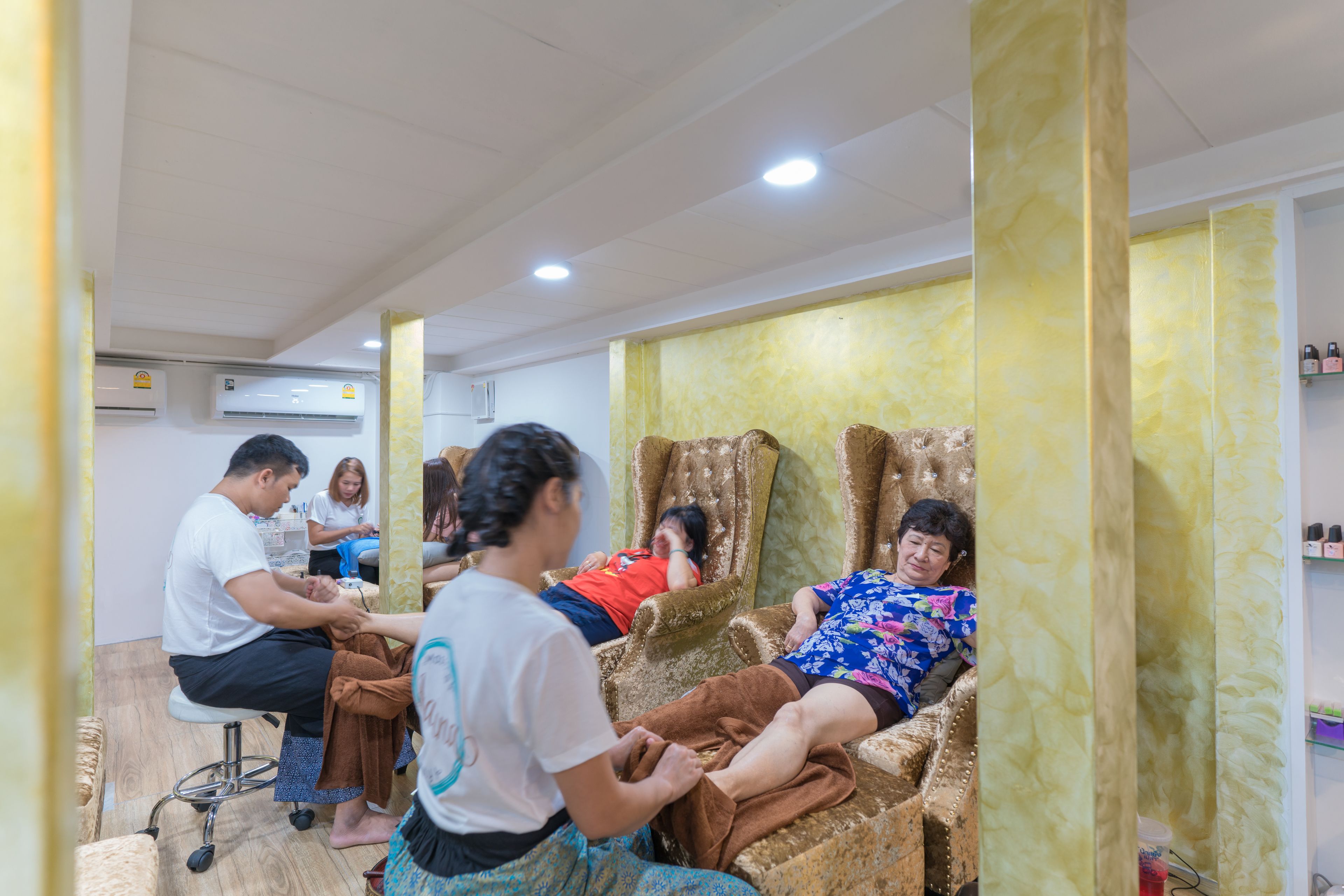 Een kamer met een massagestoel, een massagetafel en een persoon die een massage ontvangt.