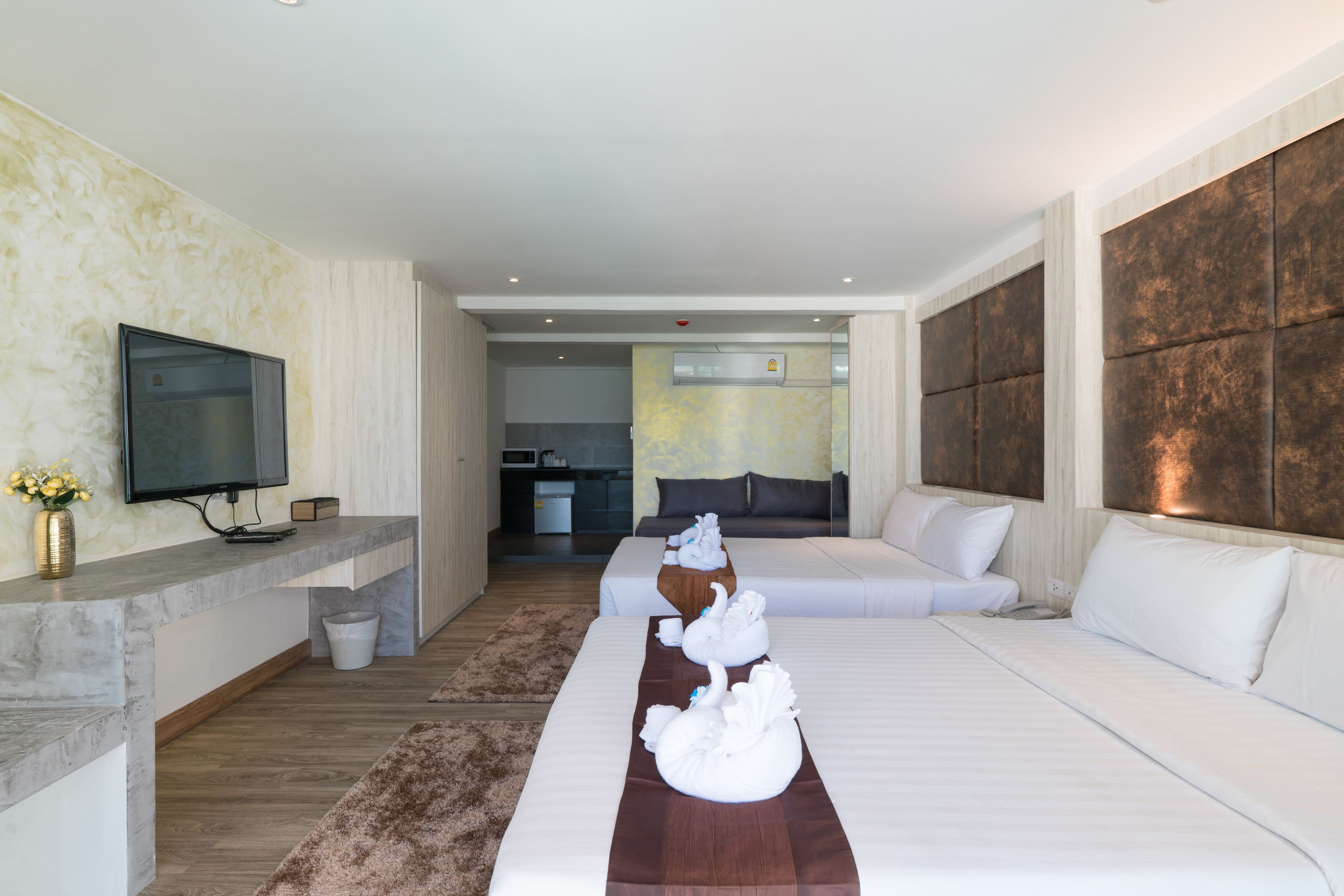 A hotel room with a bed, a TV, a small kitchen area, and a bathroom.