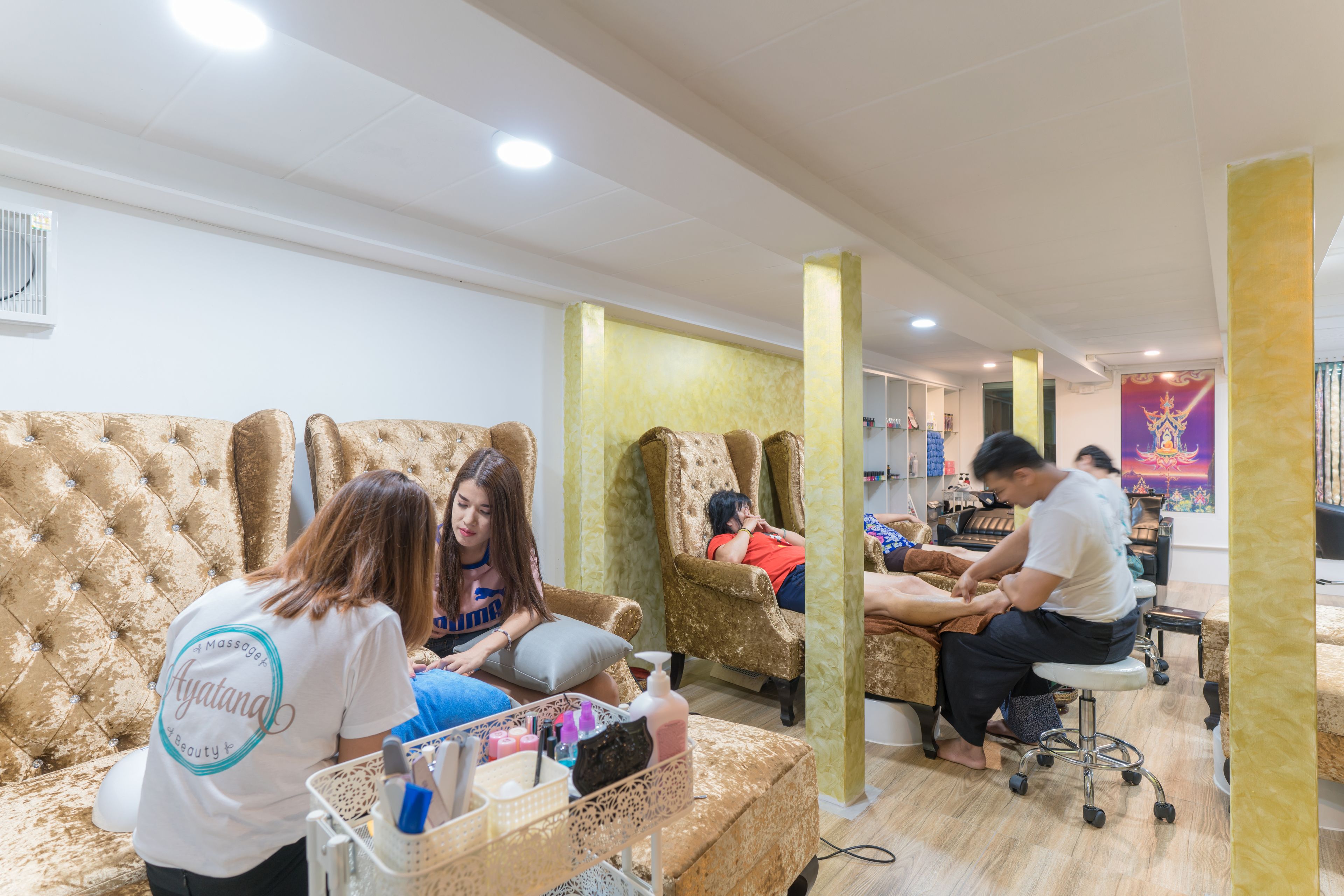 A salon with a tufted sofa, a massage chair, and a nail station.