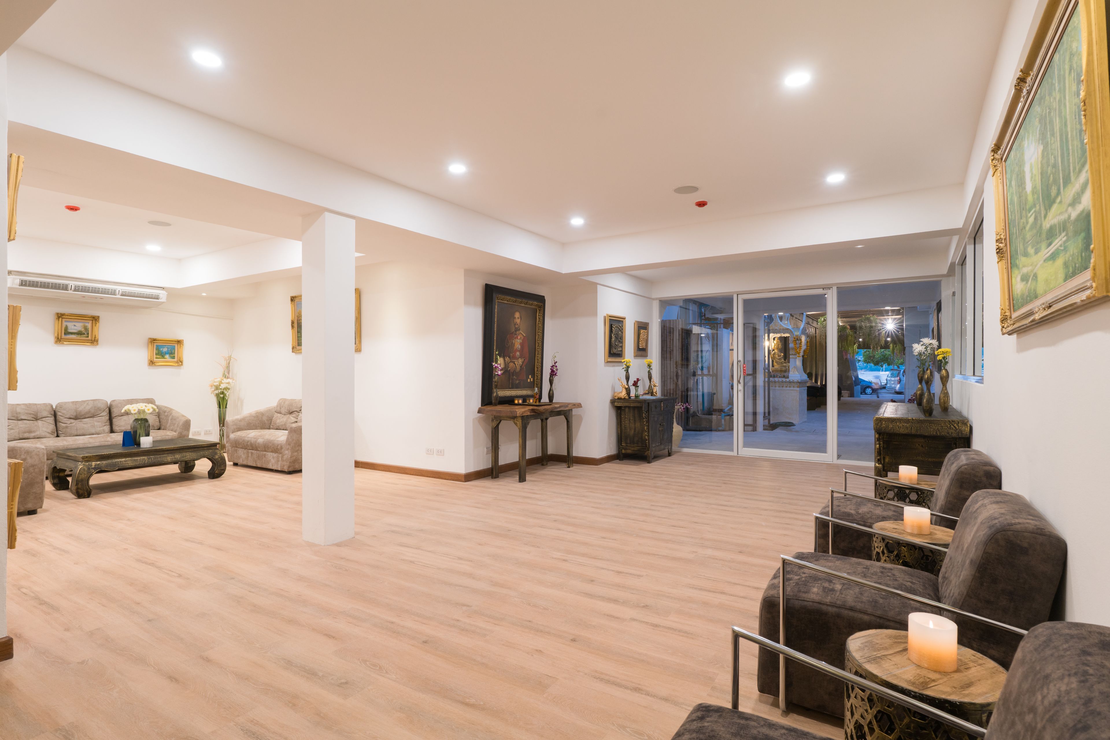 A spacious living area with a wooden floor, a sofa set, a coffee table, and a painting on the wall.