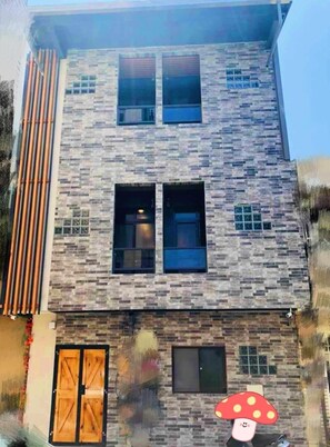 A modern building with a brick facade, multiple windows, and a wooden door. - Lugang Back Inn (Lukang)