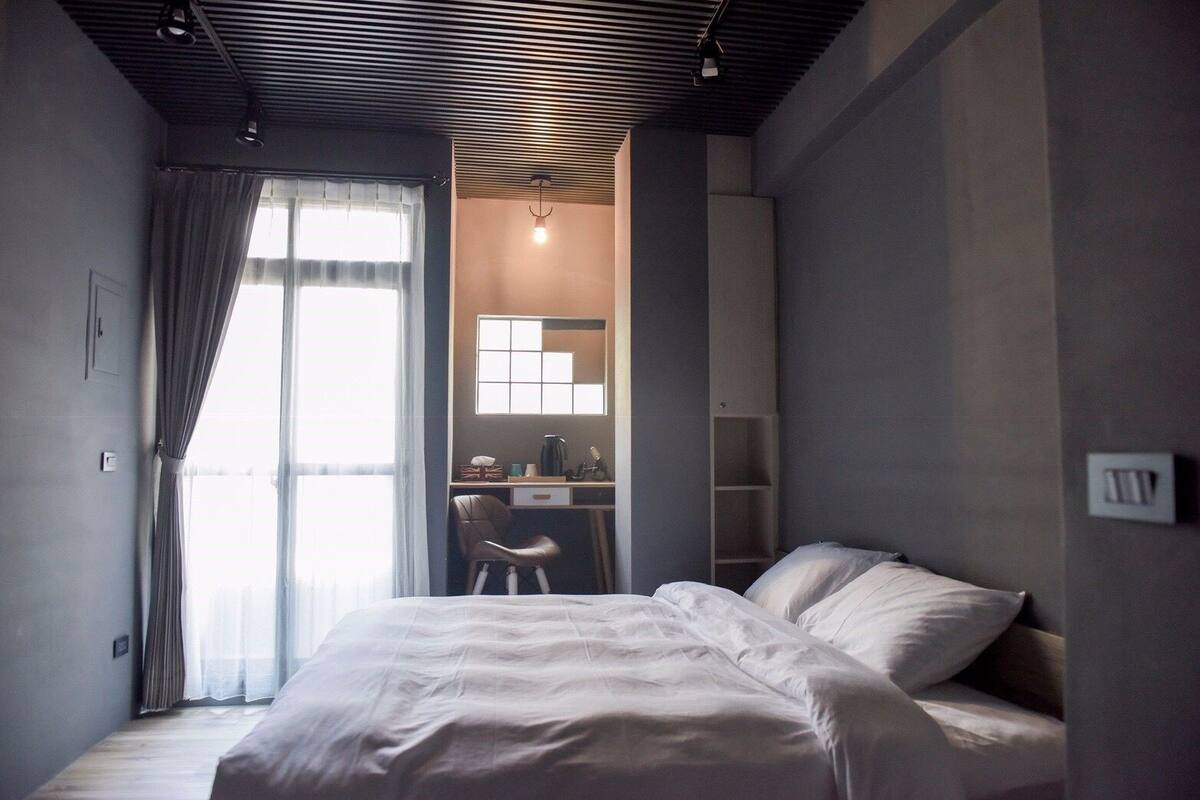 A bedroom with a bed, a desk, and a chair.