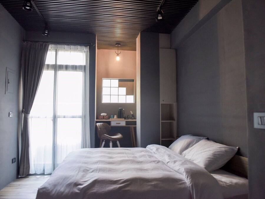 A bedroom with a bed, a desk, and a chair.