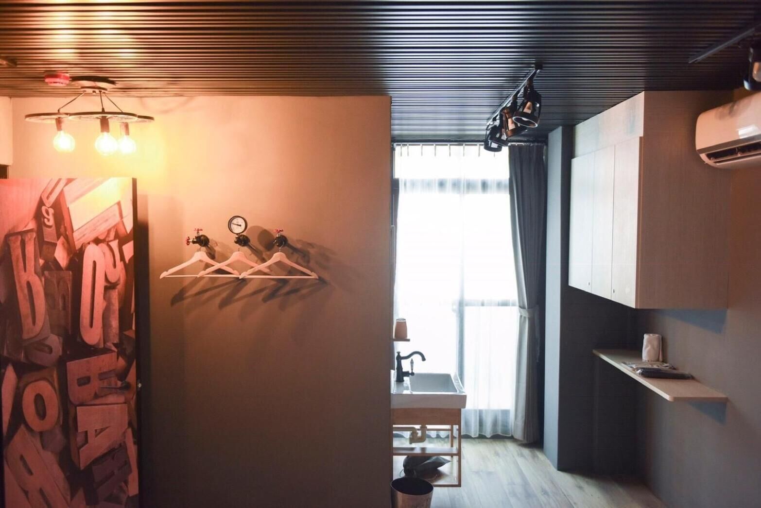 Una cocina moderna con techo de madera, lámpara colgante y ventana con cortinas.