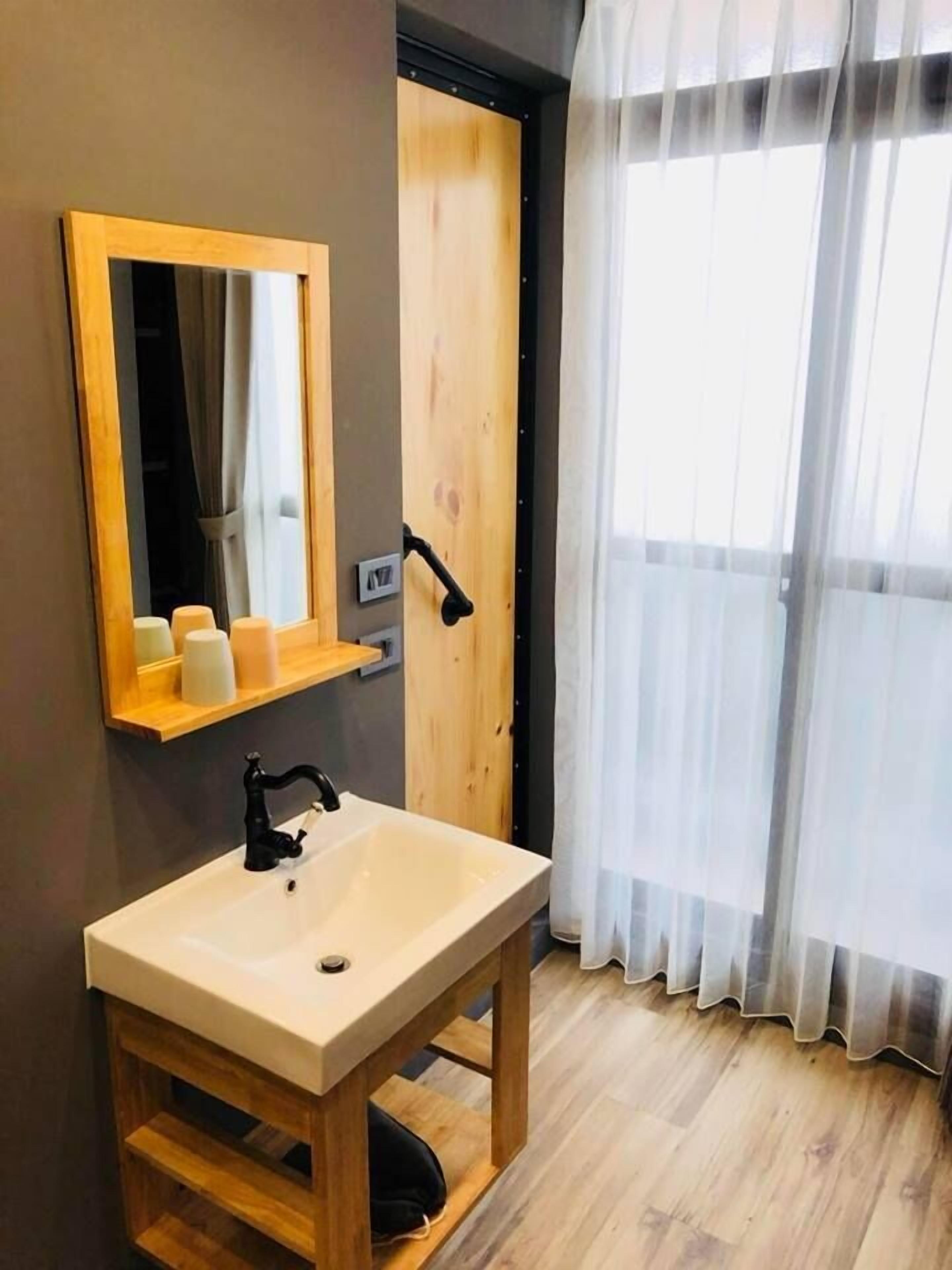 Un baño con tocador de madera, un espejo, un lavabo y una puerta con picaporte.