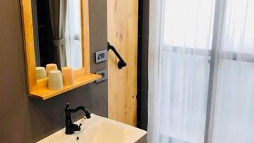 Un baño con tocador de madera, un espejo, un lavabo y una puerta con picaporte.
