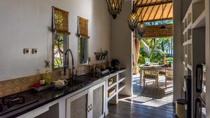 A kitchen with a black countertop, white cabinets, and a window with a bamboo blind.
