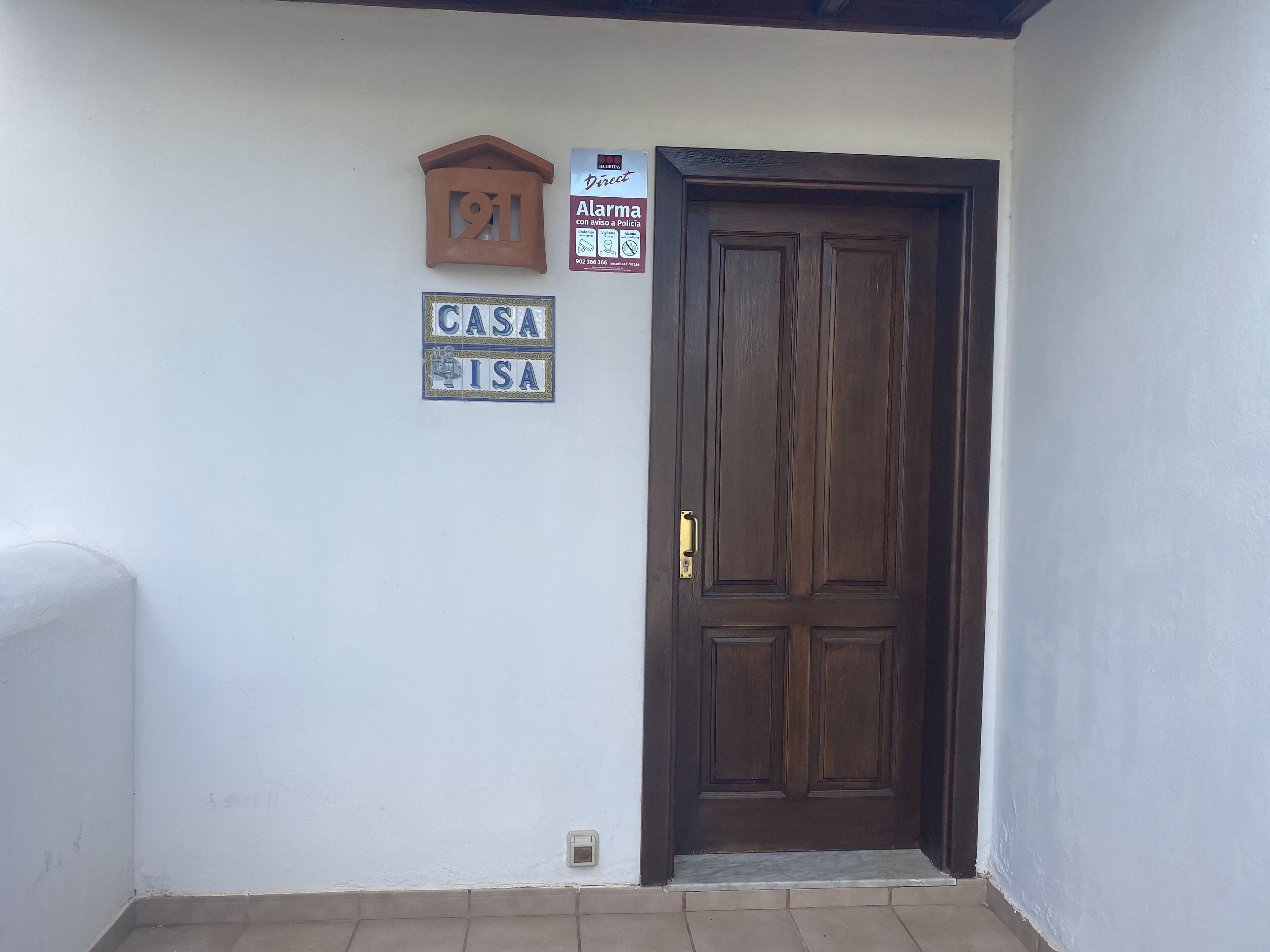 Una puerta de madera con un buzón y una placa de casa en la pared.