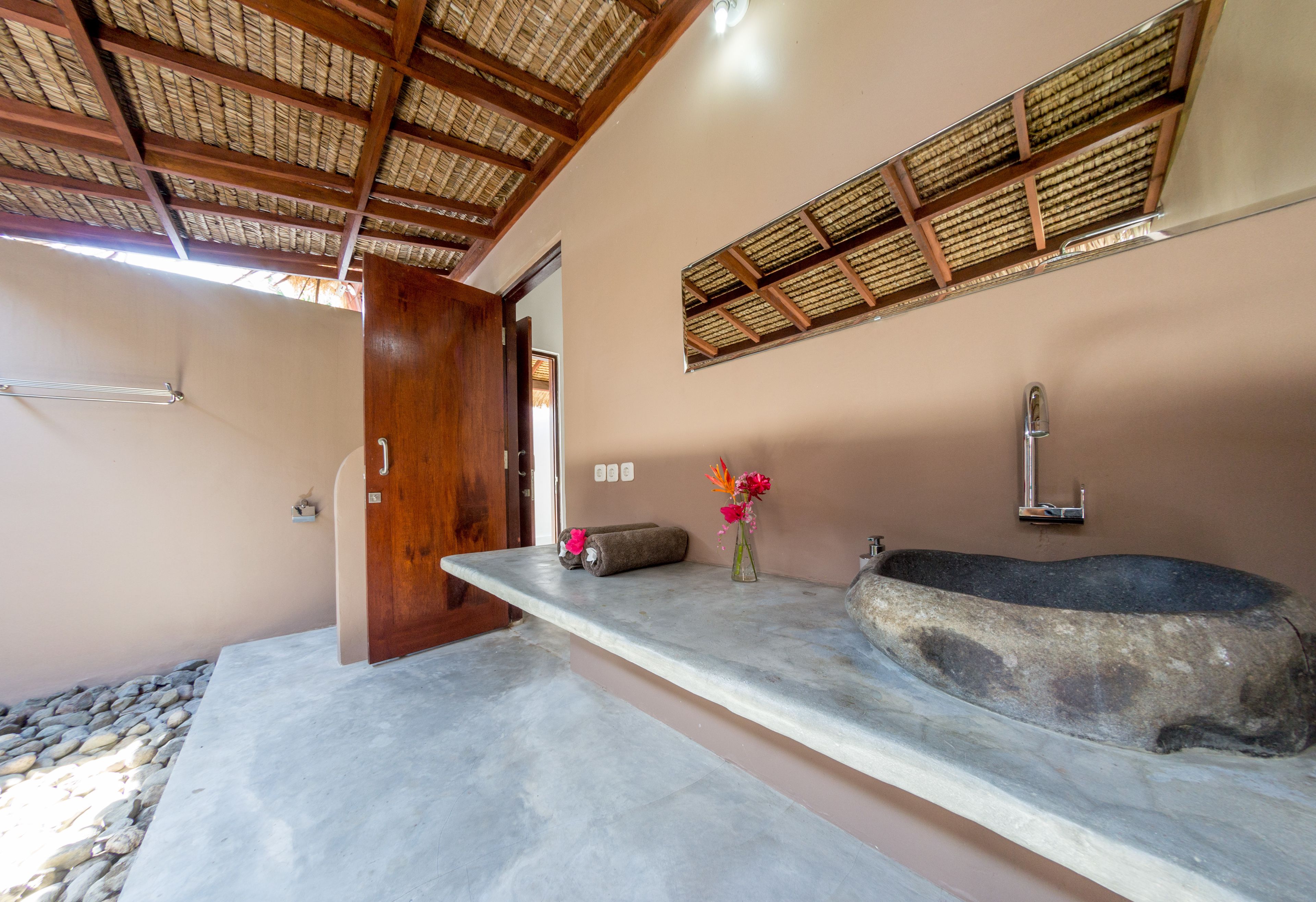 Une salle de bain avec un lavabo en pierre, une porte en bois et un plafond orné de poutres apparentes.