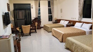 Habitación de hotel con dos camas, un escritorio, una silla, un televisor y un ventanal con cortinas.