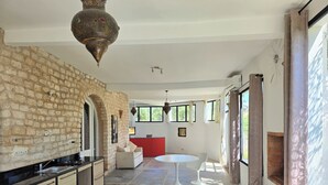 Una cocina moderna con una pared de piedra, un comedor con una mesa roja y un amplio ventanal.