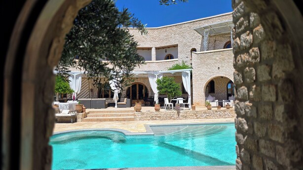 Un patio con piscina, mobiliario exterior y arquitectura de piedra.