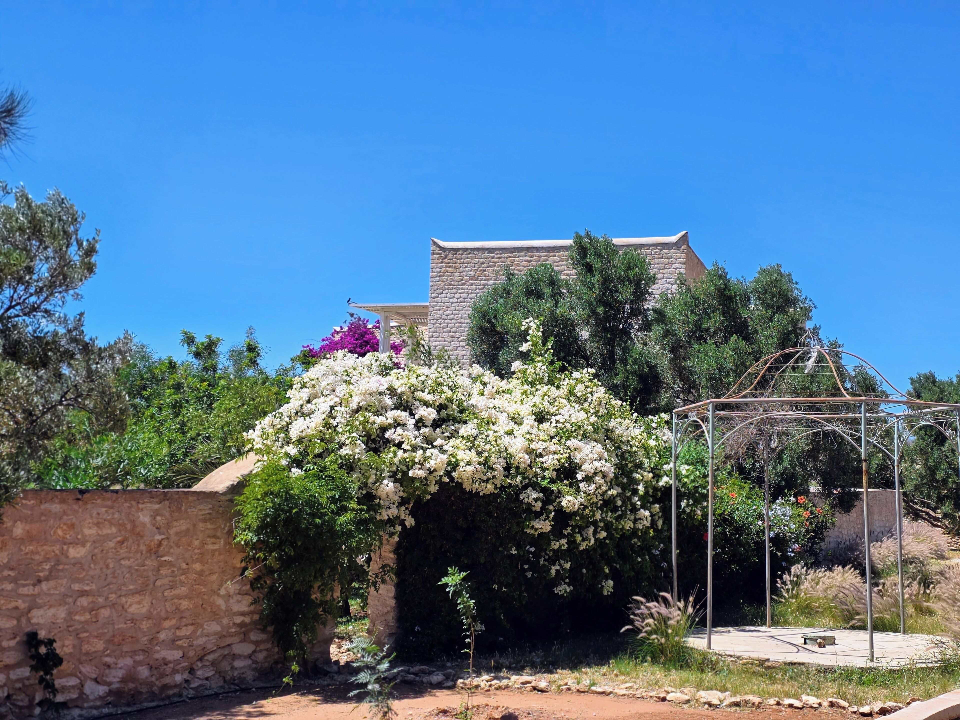 Un bâtiment en pierre doté d’un jardin et d’une structure métallique.