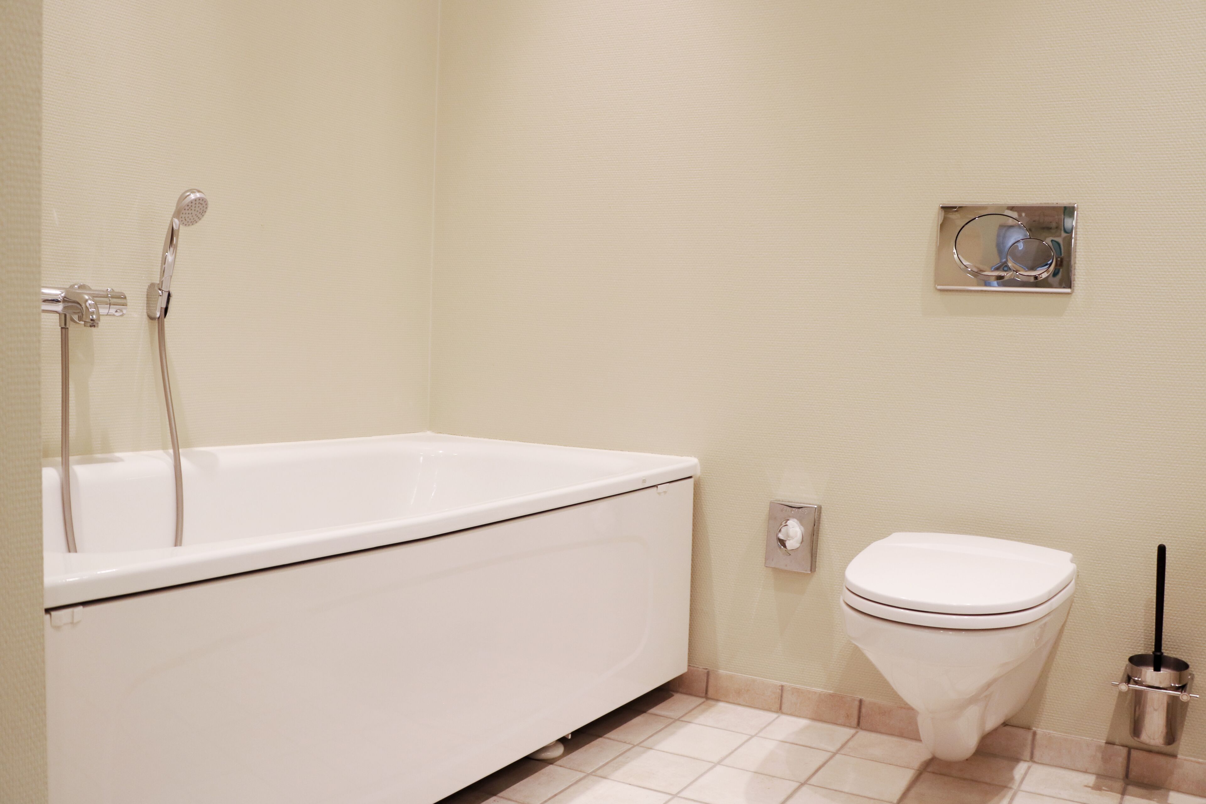 Un bagno con una vasca da bagno bianca, un water e un asciugamani ad aria montato a parete.