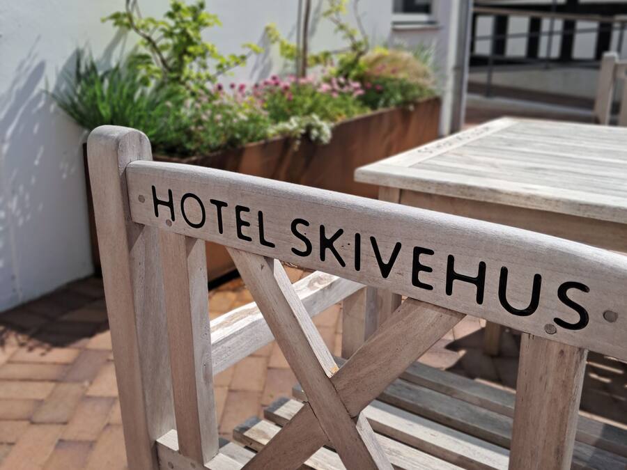 Una silla de madera con la inscripción "HOTEL SKIVEHUS" en el respaldo.