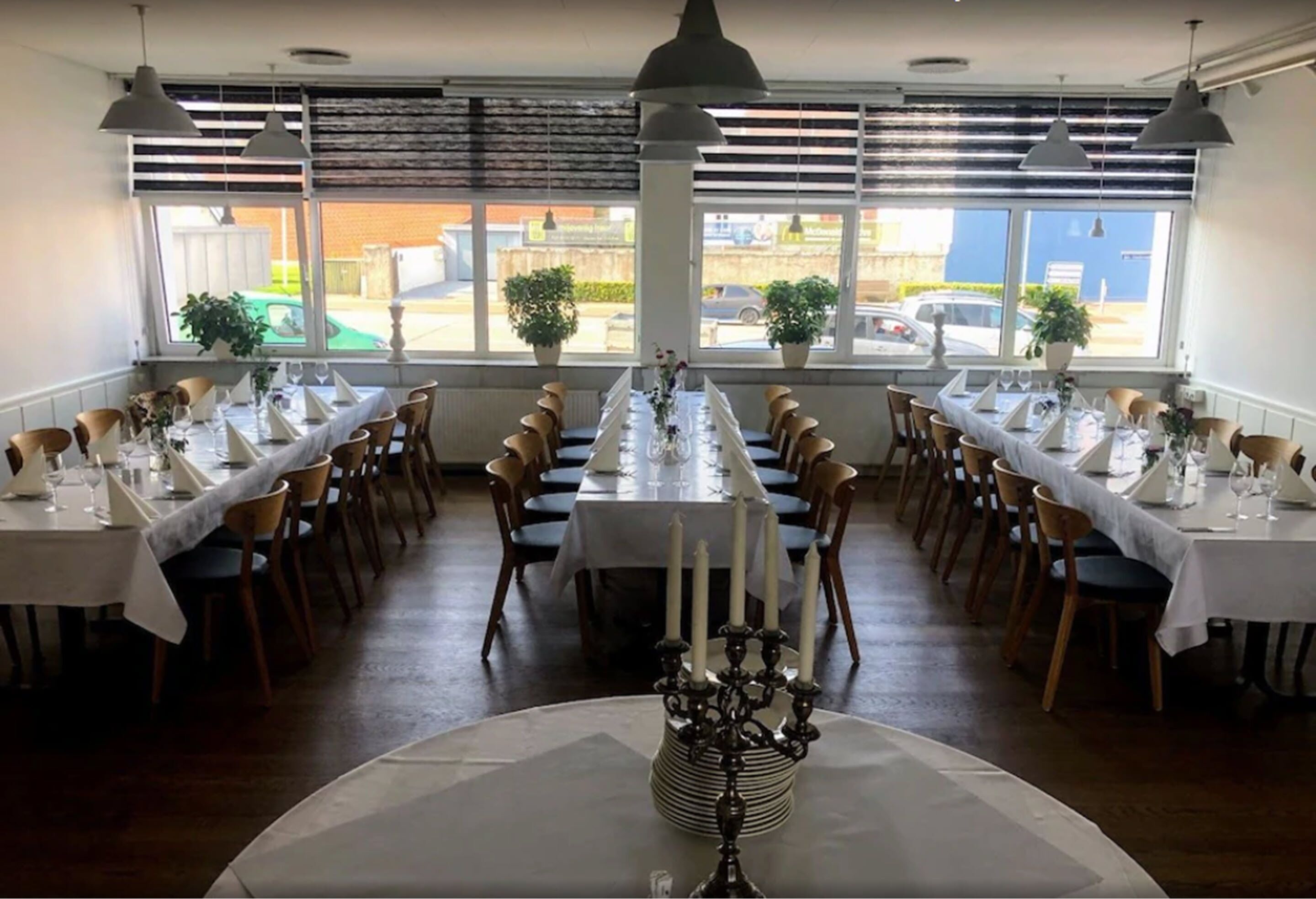 A restaurant with long tables, white tablecloths, and candle centerpieces.