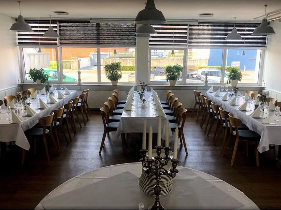 A restaurant with long tables, white tablecloths, and candle centerpieces.