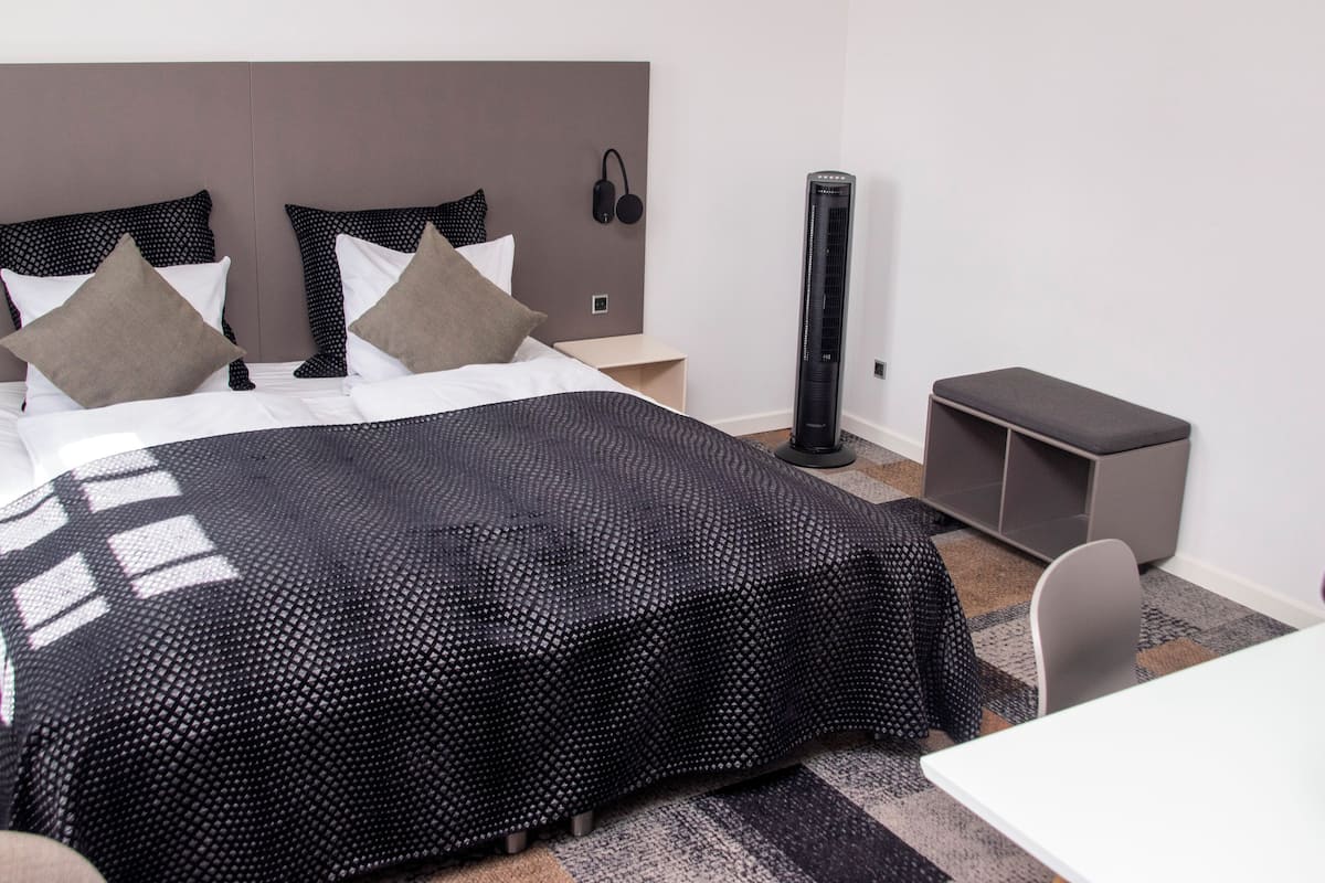 Una habitación de hotel moderna con una cama grande, un escritorio y una silla.