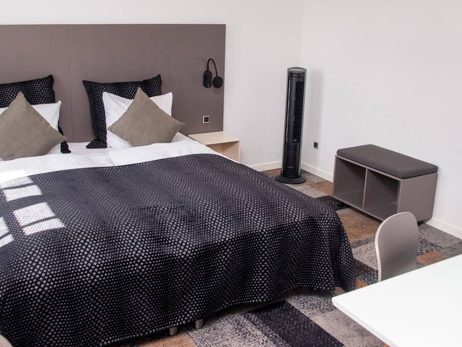 Een moderne hotelkamer met een groot bed, een bureau en een stoel.