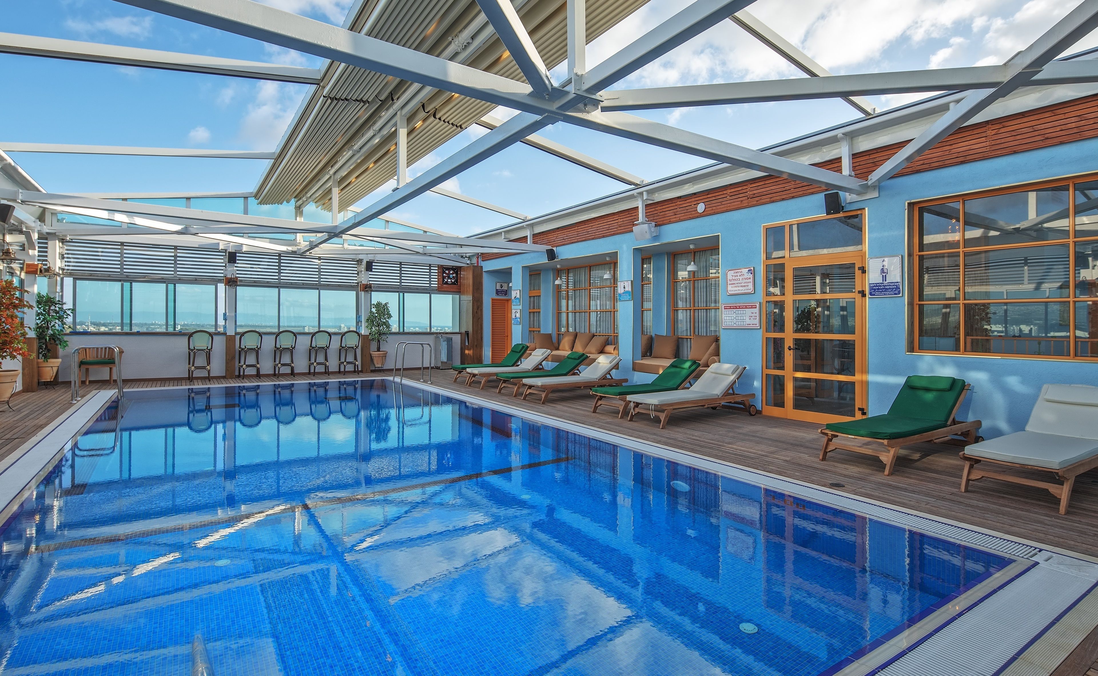 Une piscine dotée de chaises longues et d’un toit en verre.