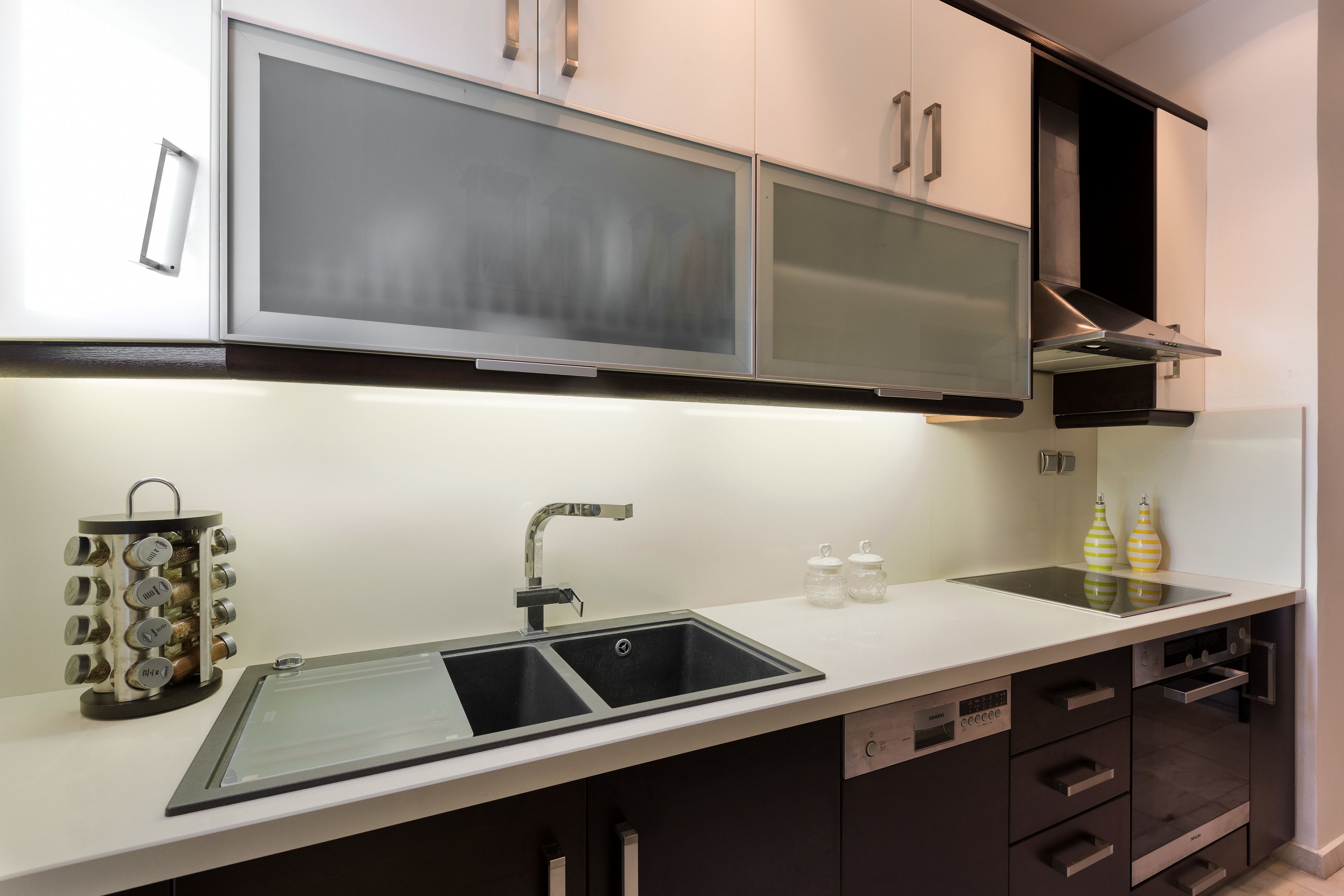 A modern kitchen with a stainless steel sink, double doors, and a built-in oven.
