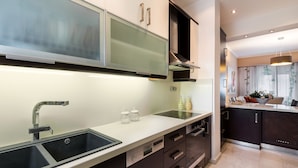 Een moderne keuken met een dubbele spoelbak, roestvrijstalen apparatuur en donkere kastjes.
