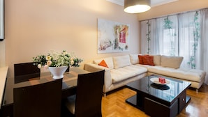Een woonkamer met een bank, een eettafel met stoelen, een salontafel en een schilderij aan de muur.