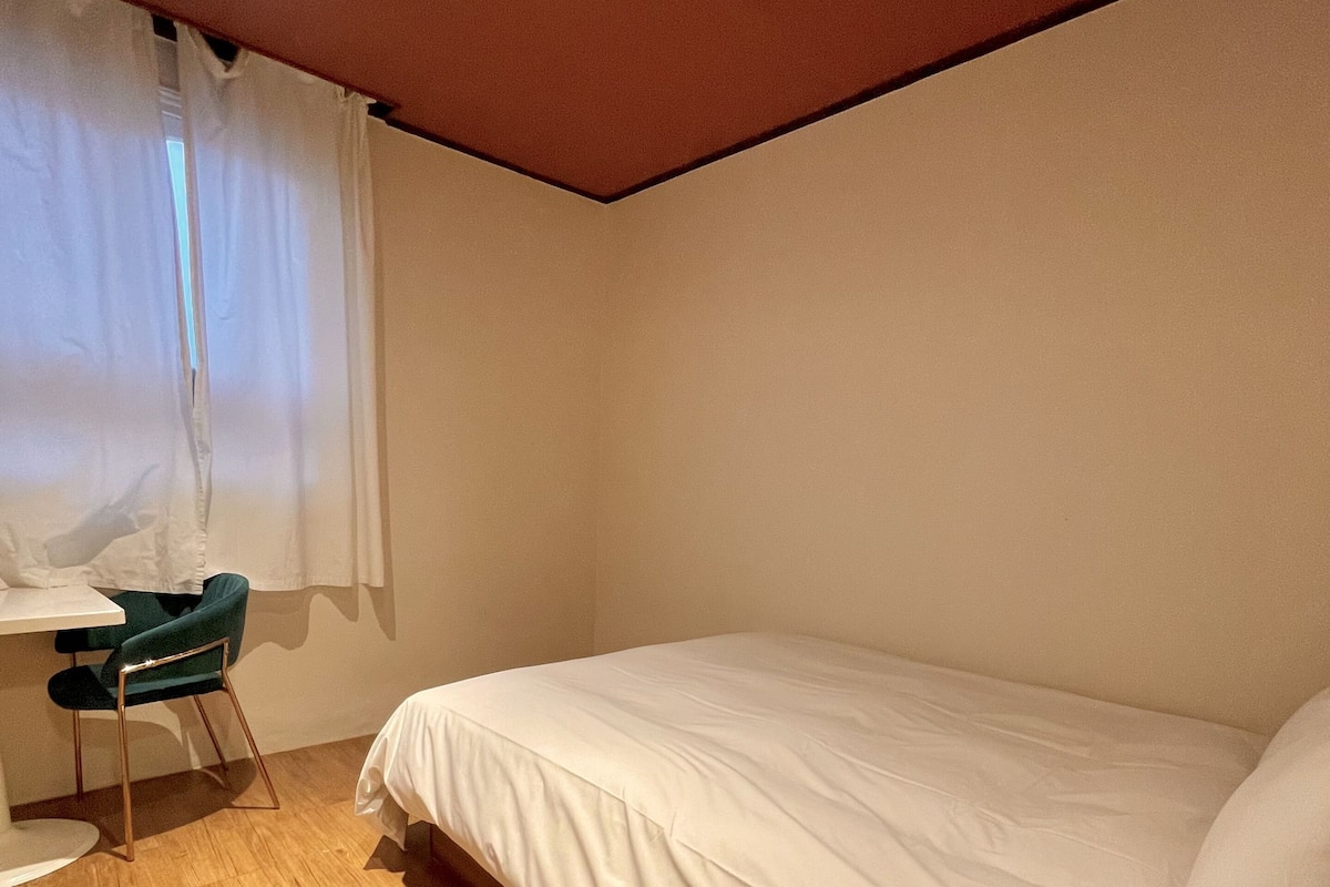 Huone, jossa on sänky, työpöytä ja tuoli.