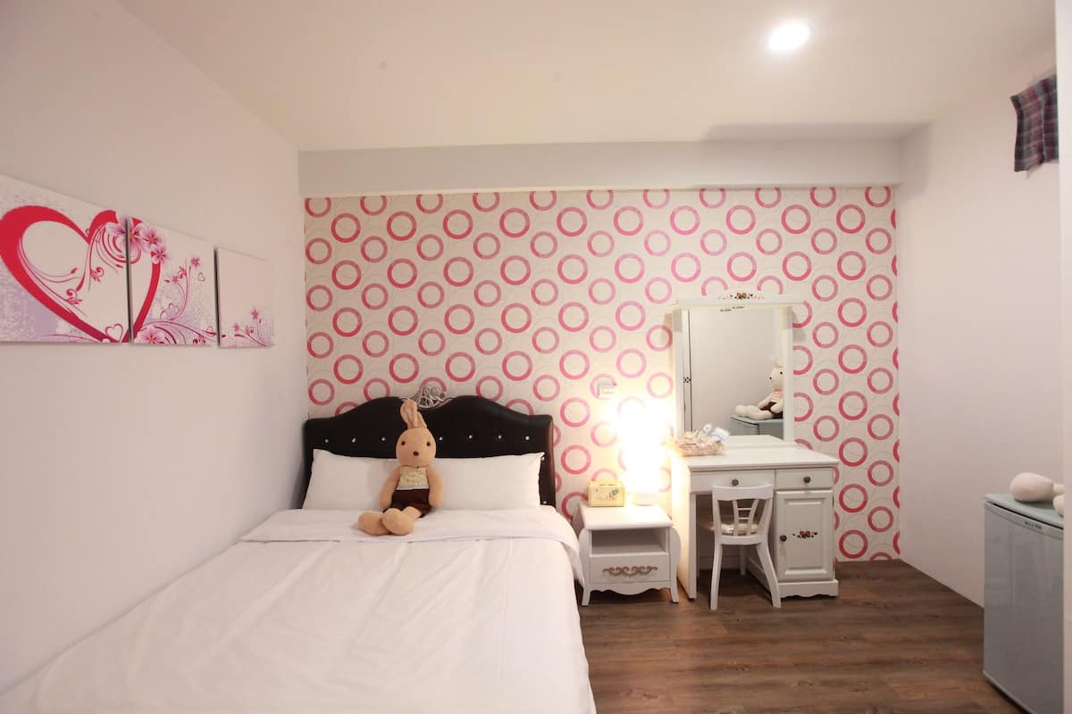 A bedroom with a bed, a nightstand, a dresser, and a mirror.