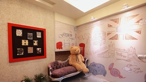 A cozy room with a plush sofa, a teddy bear, and a wall decorated with various doodles and drawings. - Fasiter B&B (Hualien City)
