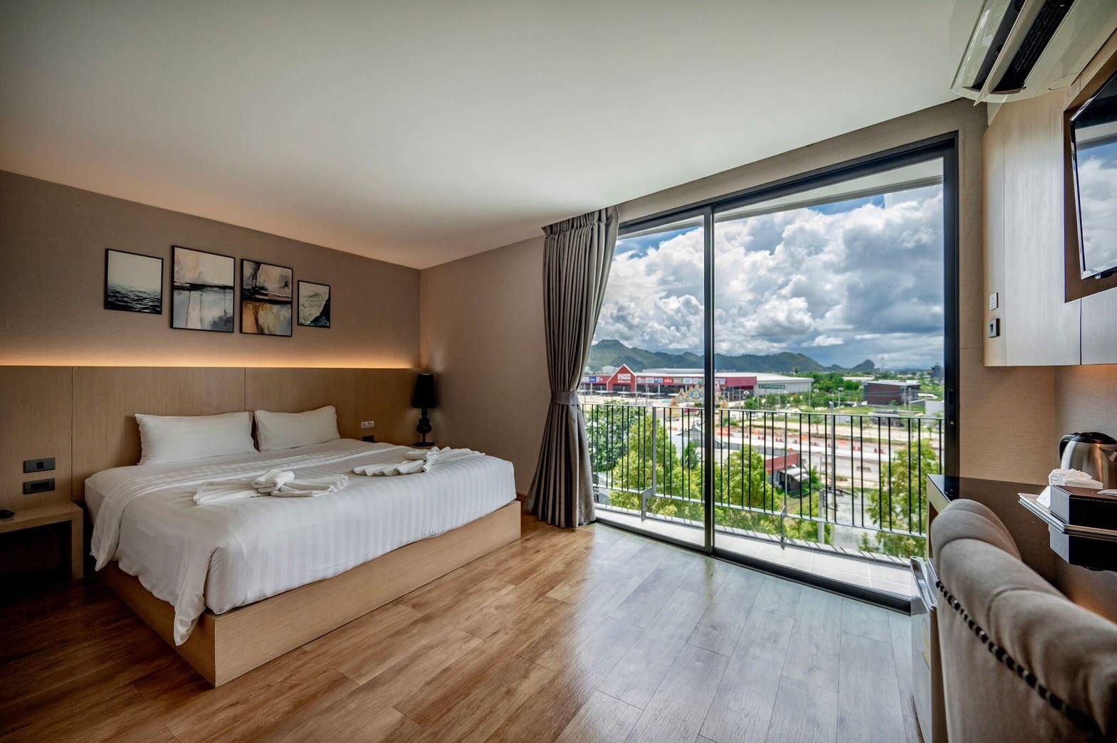 A hotel room with a large bed, a view of the cityscape, and a balcony.