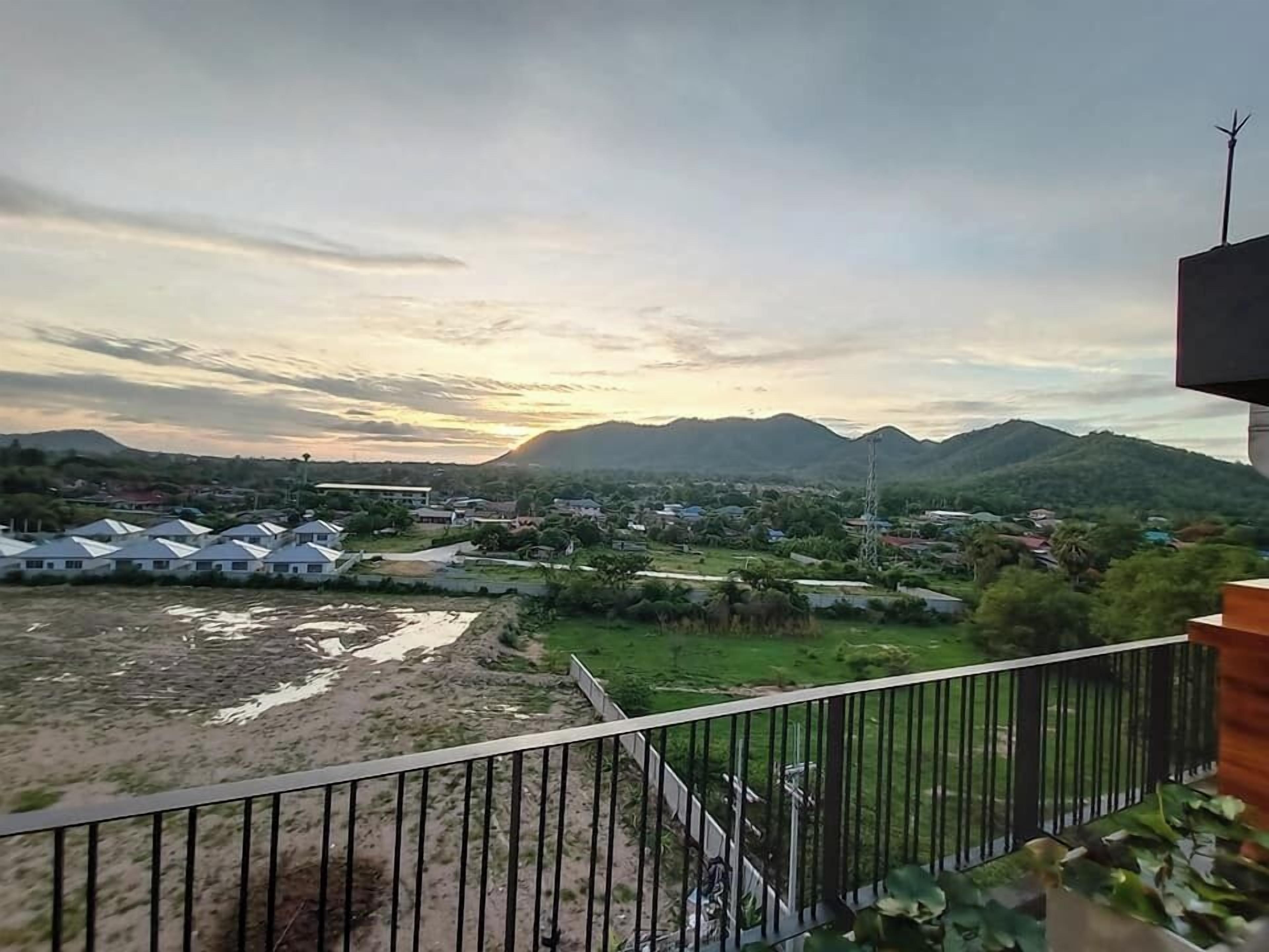 Une vue depuis un balcon donnant sur un quartier résidentiel, avec des maisons et une montagne en arrière-plan.