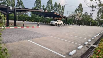 A parking area with a white car, marked parking spaces, and a covered walkway.